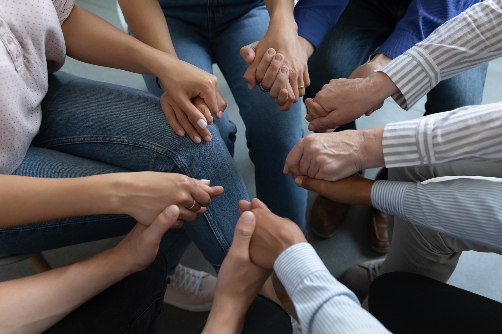 Group of anonymous addicted prayers praying on therapy meeting